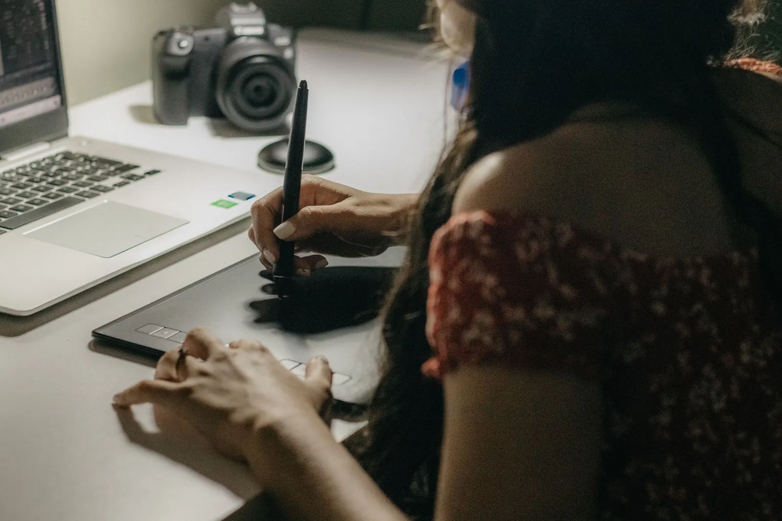 A designer marking up an interface on a pen tablet in a dimly lit studio